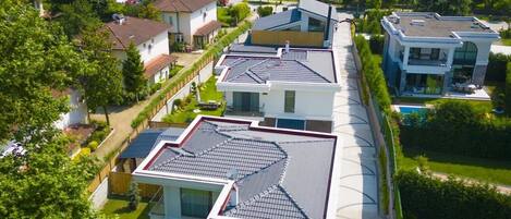 Un moderno complejo residencial con varias casas, una piscina y un paisaje montañoso de fondo.