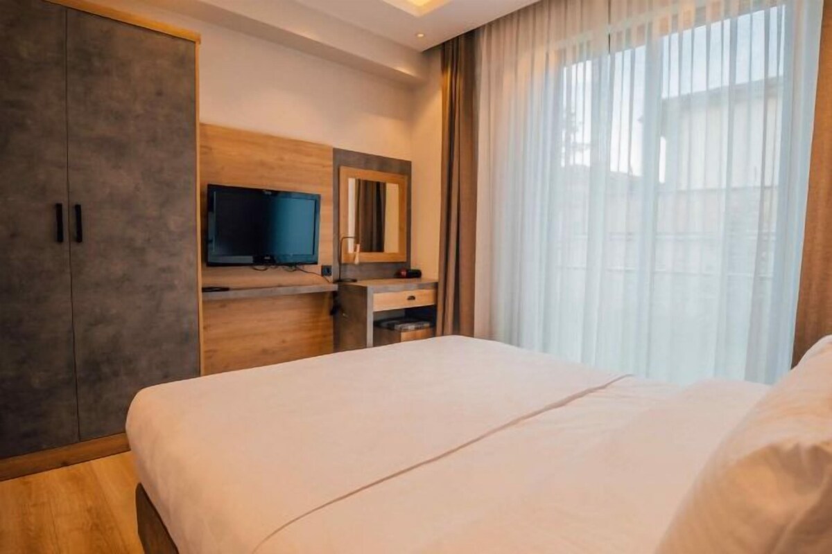 Een hotelkamer met een bed, een televisie, een spiegel en een kledingkast.
