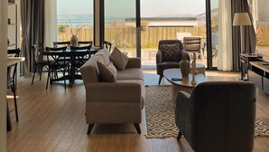 Un salon spacieux avec une grande fenêtre, un lustre et une vue sur la plage.