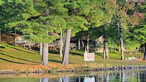 Vista su un lago con un cartello per un albergo, circondato da alberi e un'area verde.