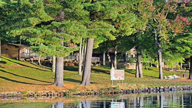 A lakeside view with a sign for a hotel, surrounded by trees and a grassy area. - Chanticleer Inn 37 (Washington)