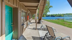 A covered walkway with a green door, outdoor seating, and a view of a lake. - Chanticleer Inn 37 (Washington)