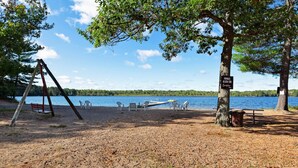 Une plage privée équipée d’une balançoire, de tables de pique-nique et de chaises.