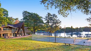 Un hôtel situé au bord d’un lac, doté d’un court de tennis, d’une terrasse en bois et offrant une vue sur le lac.