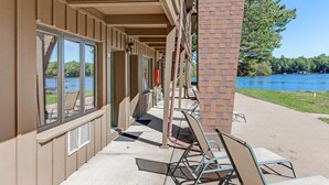 Un espace extérieur abrité, avec vue sur un lac, comprenant une rangée de chaises et un pilier en briques.