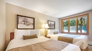 A hotel room with two beds, a large window, and two framed pictures on the wall. - Chanticleer Inn 39 (Eagle River)