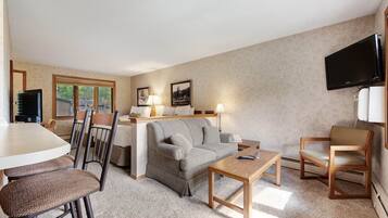 Ein gemütlicher Wohnbereich mit einer Couch, zwei Sesseln, einem Couchtisch, einem Fernseher und einem Essbereich mit Tisch und Stühlen.