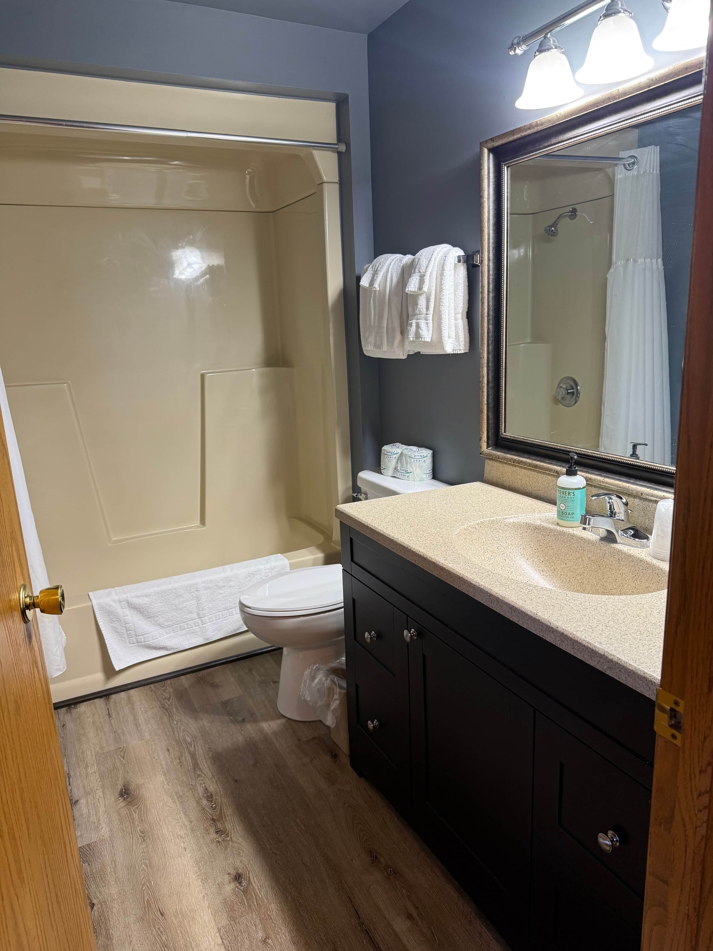 A bathroom with a shower, toilet, sink, and a mirror.