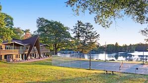 Un hôtel situé au bord d’un lac, doté d’un court de tennis, d’une terrasse en bois et offrant une vue sur le lac.