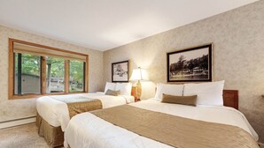 Une chambre avec deux lits, une fenêtre et des tableaux encadrés accrochés au mur.