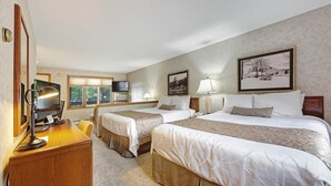 A hotel room with two beds, a desk with a lamp, a television, and framed pictures on the wall. - Chanticleer Inn 44 (Eagle River)