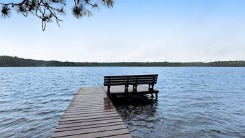 A wooden pier extending into calm water with a bench at the end.