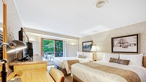 Hotellihuone, jossa on kaksi sänkyä, työpöytä tietokoneella, tuoli ja näkymä ulos.