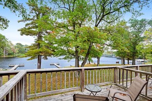 A wooden deck with a table and chairs overlooking a lake.