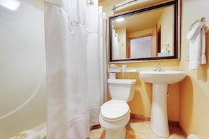 A bathroom with a toilet, sink, and shower curtain. - Chanticleer Inn 54 (Eagle River)