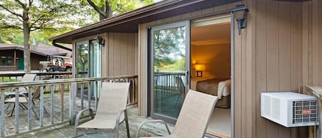 A wooden deck with outdoor seating and a sliding glass door leading to a bedroom.
