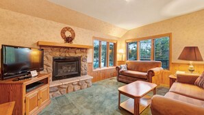 Un salón acogedor con chimenea de piedra, televisor y asientos cómodos.