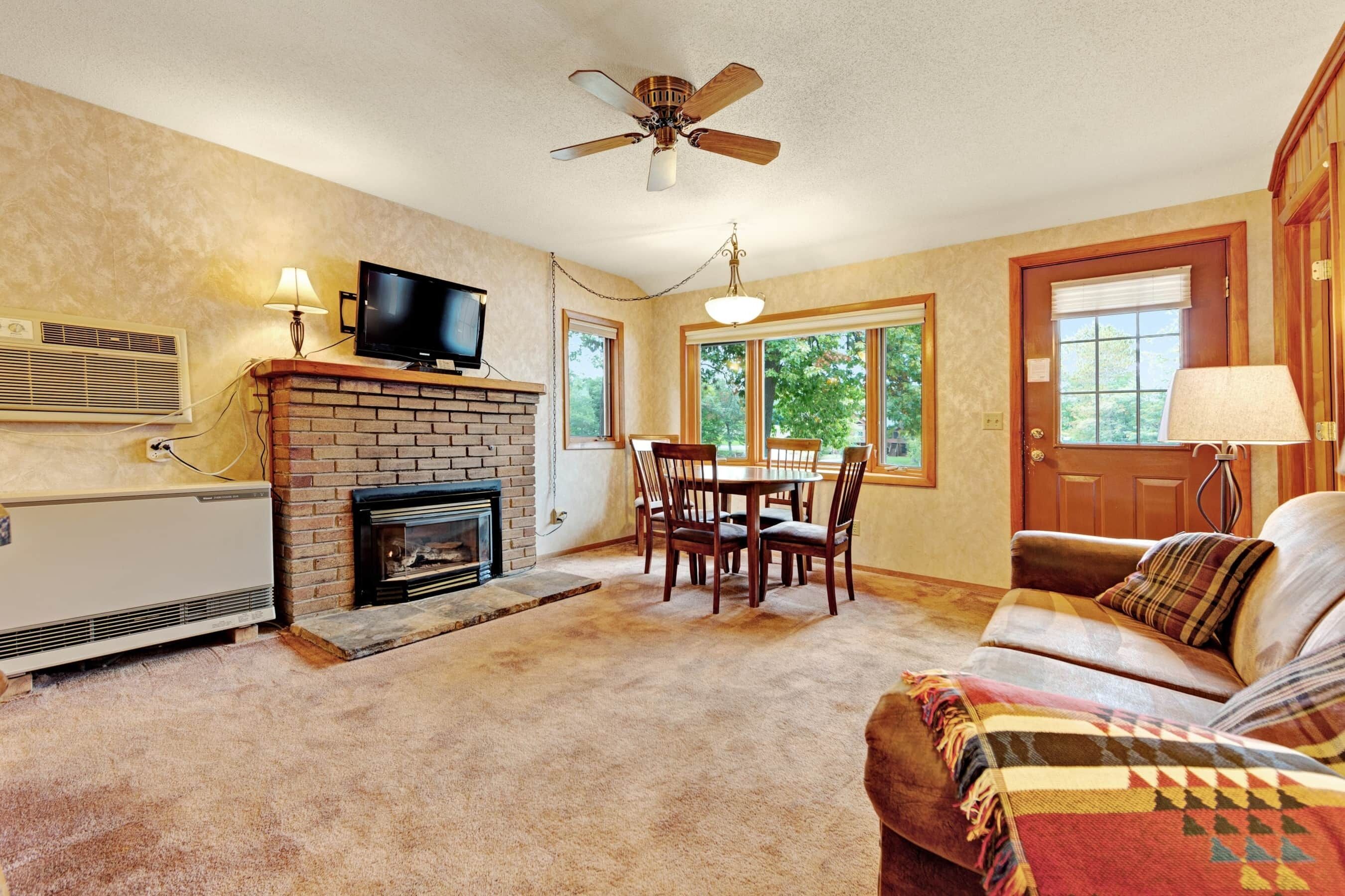 Una sala de estar con chimenea, televisor, mesa de comedor y asientos cómodos.