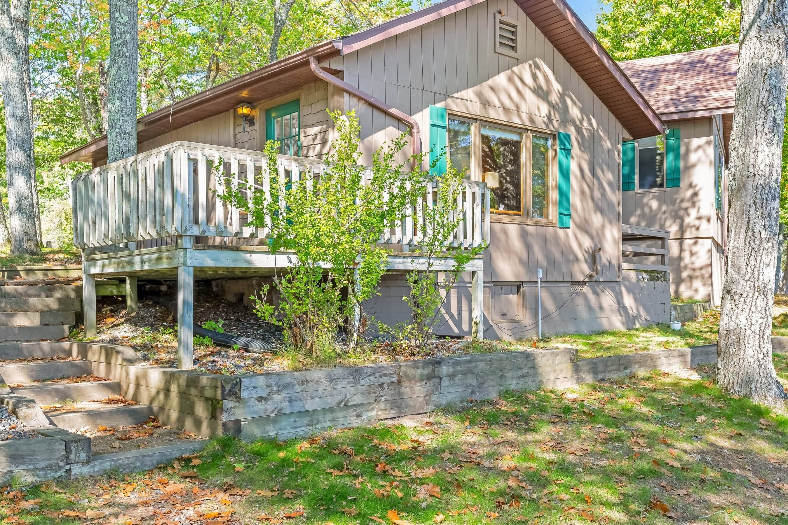A cabin with a wooden deck, a small porch, and a staircase leading to the entrance.