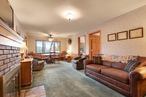 A cozy living room with a fireplace, leather sofa, and a dining area with wooden furniture. - Chanticleer Inn Villa 7 (Eagle River)