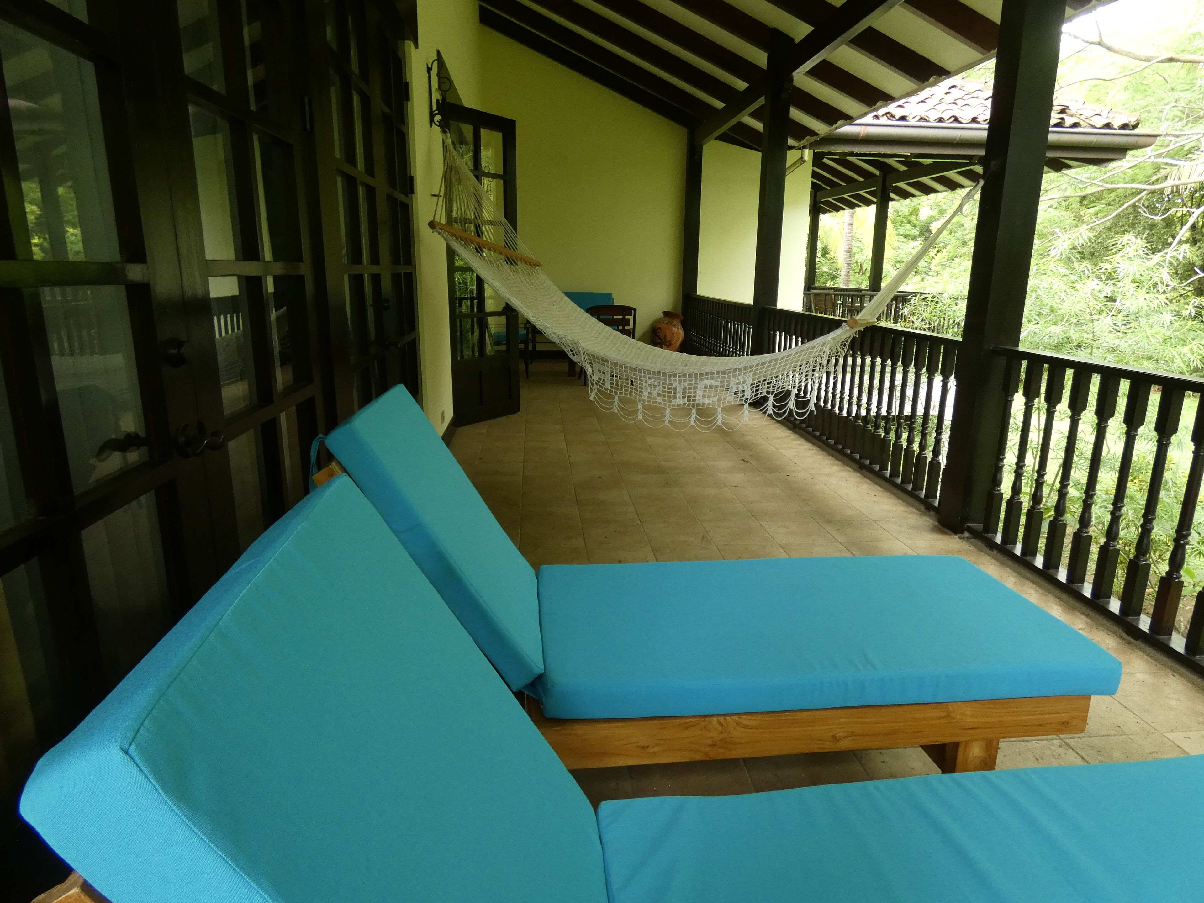 Un espace extérieur abrité, aménagé avec des bancs bleus dotés de coussins et un hamac.