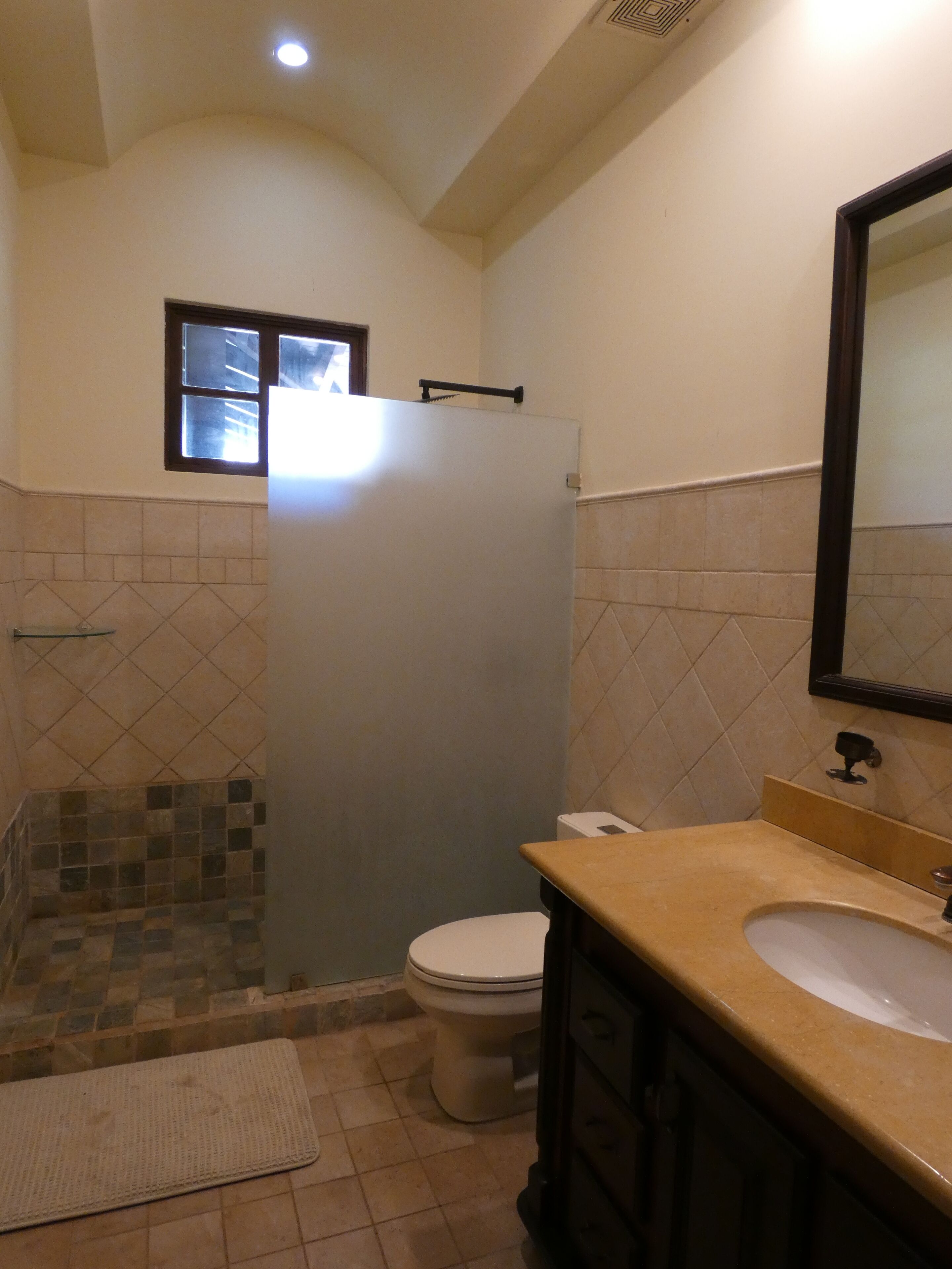 Un baño con inodoro, lavamanos y zona de ducha.