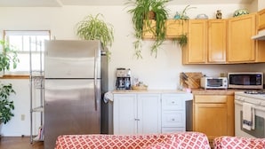 A compact kitchen with a refrigerator, microwave, and stove. There are cabinets, a coffee maker, and a plant on the counter. - sweet little casita (Santa Fe)