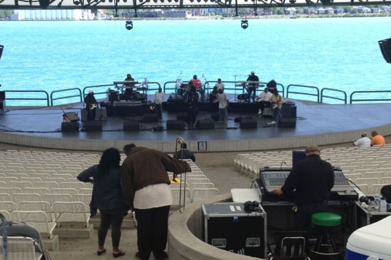 A stage with musicians and a seated audience at a waterfront venue.