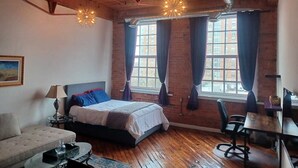 A bedroom with a bed, a desk, a chair, a lamp, and a window with curtains.