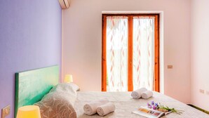 A hotel room with a bed, a lamp, a window with curtains, and a magazine on the bed. - Le Pavoncelle Bilo 1Km From The Beach (Santa Teresa di Gallura)