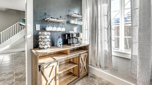 A modern kitchen with a rustic wooden counter, a coffee machine, and hanging mugs.