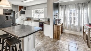 A modern kitchen with a central island, white cabinetry, and a large window.