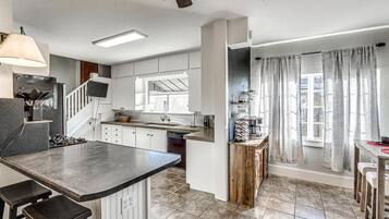 Une cuisine moderne avec un îlot central, des meubles blancs et une grande fenêtre.