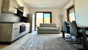 Une cuisine moderne dotée d’appareils électroménagers intégrés, un canapé gris et un coin repas avec des chaises.