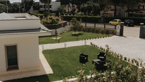 A residential area with a white building, a green lawn, and a paved driveway. - Harmony B&B (Leporano)