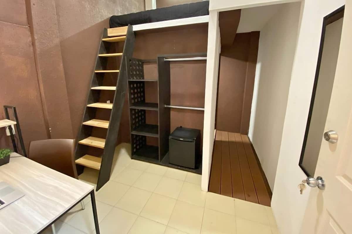Ein kleines Zimmer mit Etagenbett, Schreibtisch und einer kleinen Ablagefläche.