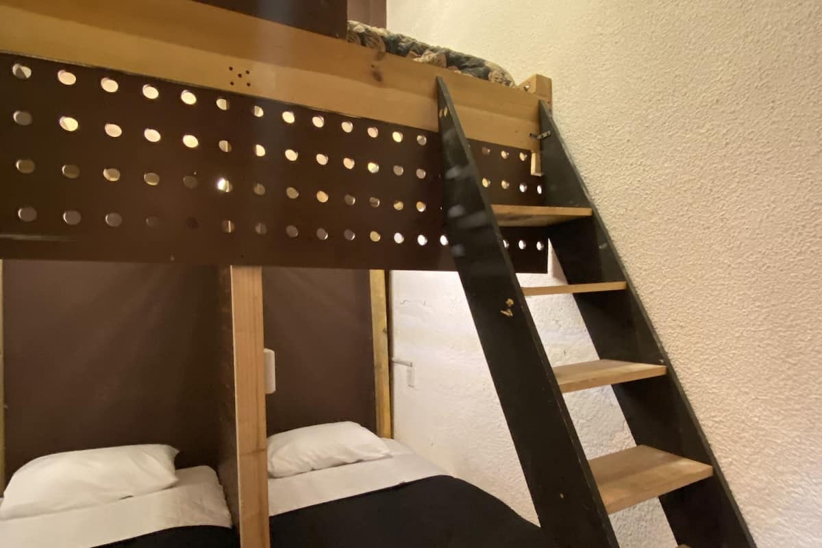 Ein Stockbett mit einer Holzleiter und einem Metallgestell.