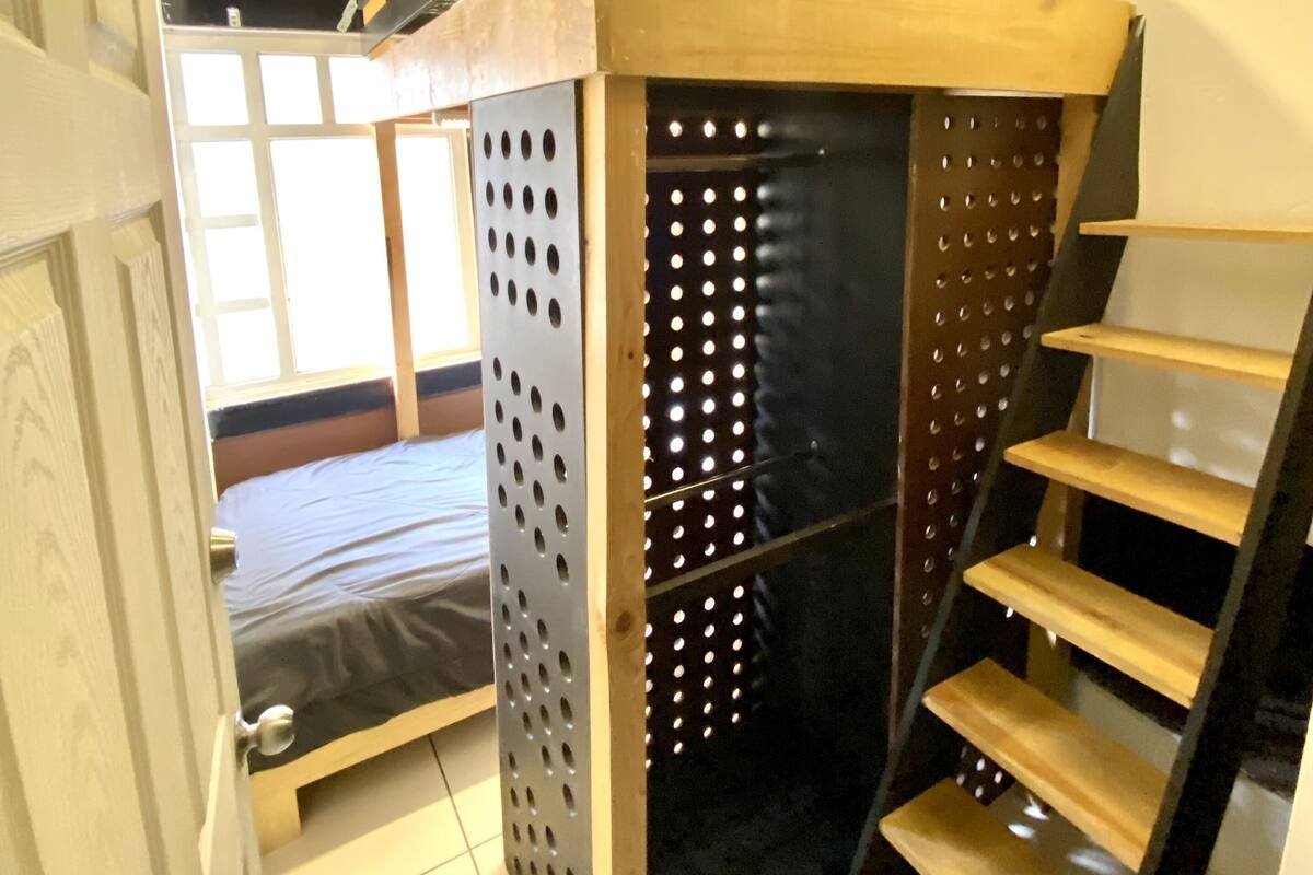 Ein kleiner Raum mit einem Etagenbett, einer kleinen Leiter und einer Tür zu einem weiteren Raum.