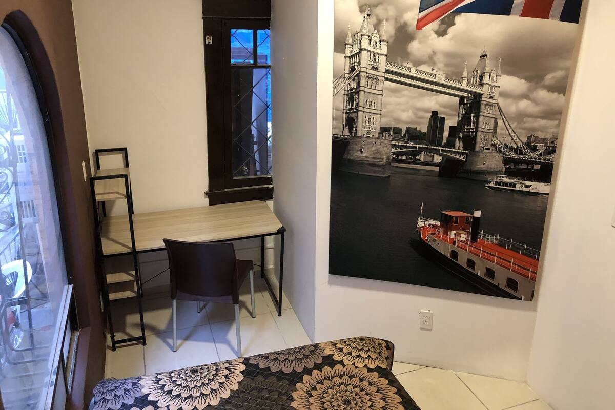 Ein Zimmer mit Schreibtisch, Stuhl und einem großen Fenster.