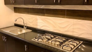 Una cocina moderna con armarios oscuros, un lavamanos de acero inoxidable y una estufa a gas.