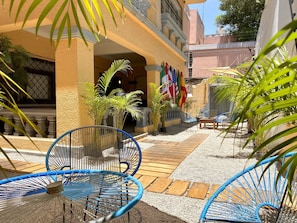 A courtyard with blue chairs, potted plants, and flags. - ROOMIES HOSTEL CENTRO MEDICO (Mexico City)