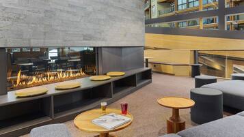 A modern lounge area with a fireplace, seating, and tables.