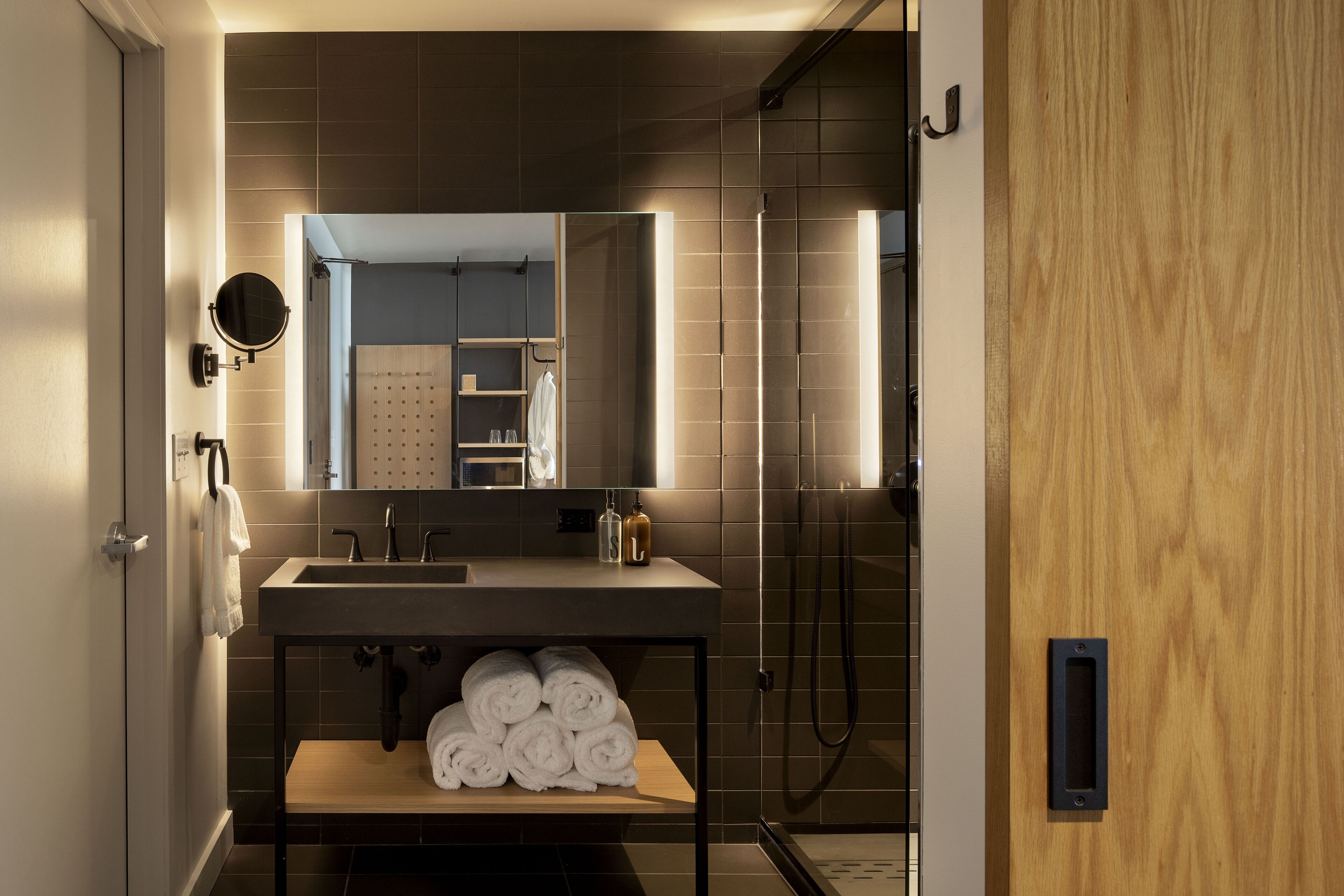 A modern bathroom with a large mirror, a sink, and a shower.