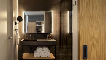 A modern bathroom with a large mirror, a sink, and a shower.