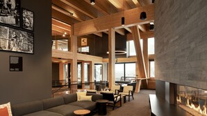 A modern interior with a sectional sofa, round tables, and a fireplace. - Humbird (Sandpoint)