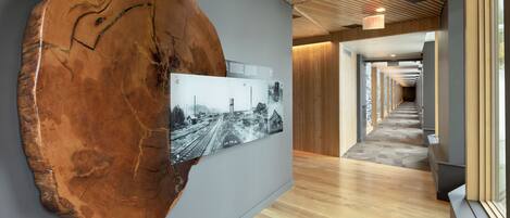 Un couloir doté d’un plancher en bois, d’une grande sculpture en bois et d’une photographie en noir et blanc accrochée au mur.