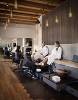 Un spa moderno con techos de madera, una zona de recepción y un área de descanso con un espejo grande.