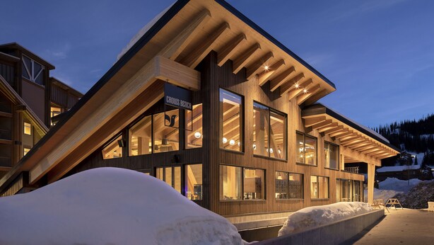 A modern building with large windows and a wooden facade, surrounded by snow. - Humbird (Sandpoint)