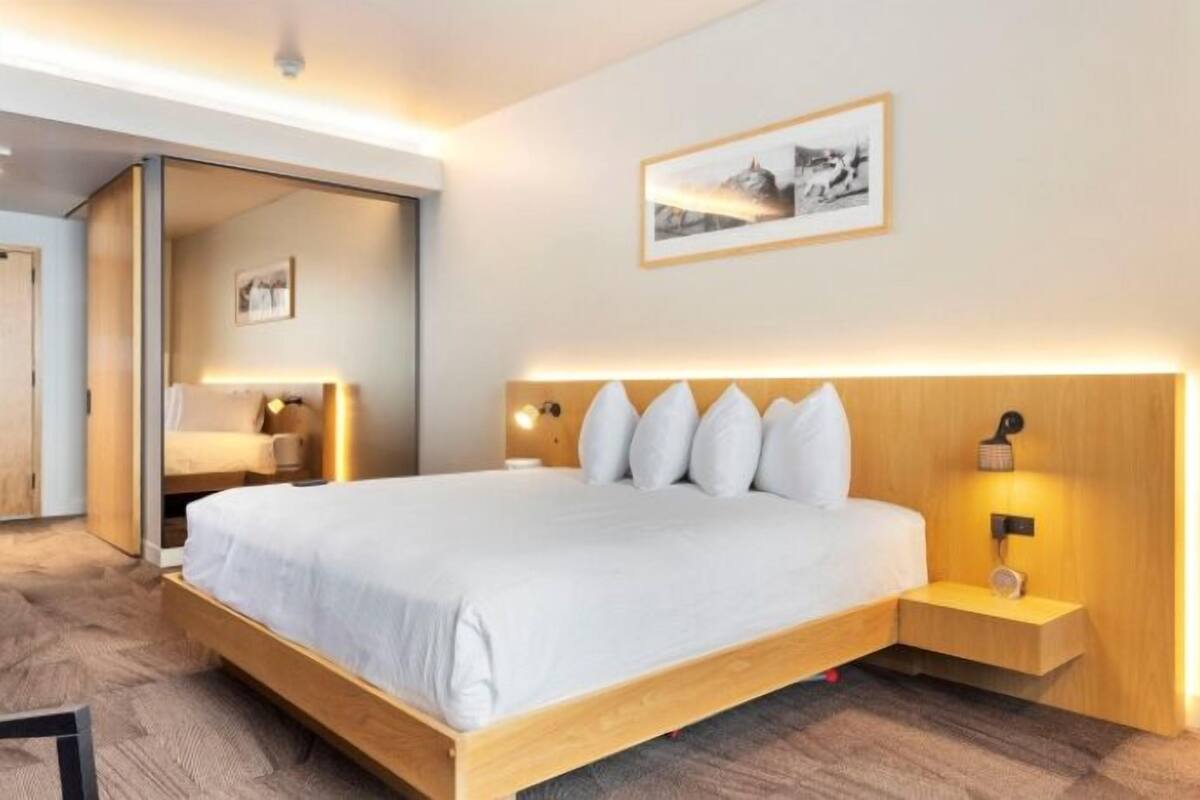 A modern hotel room with a large bed, bedside tables, and a framed picture on the wall.