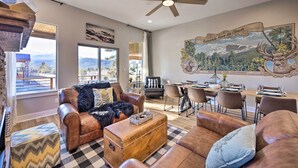 A spacious living room with leather furniture, a dining area, and a large window offering a mountain view. - Woodland Park Escape: Hot Tub & Mtn Views 331446 (Woodland Park)